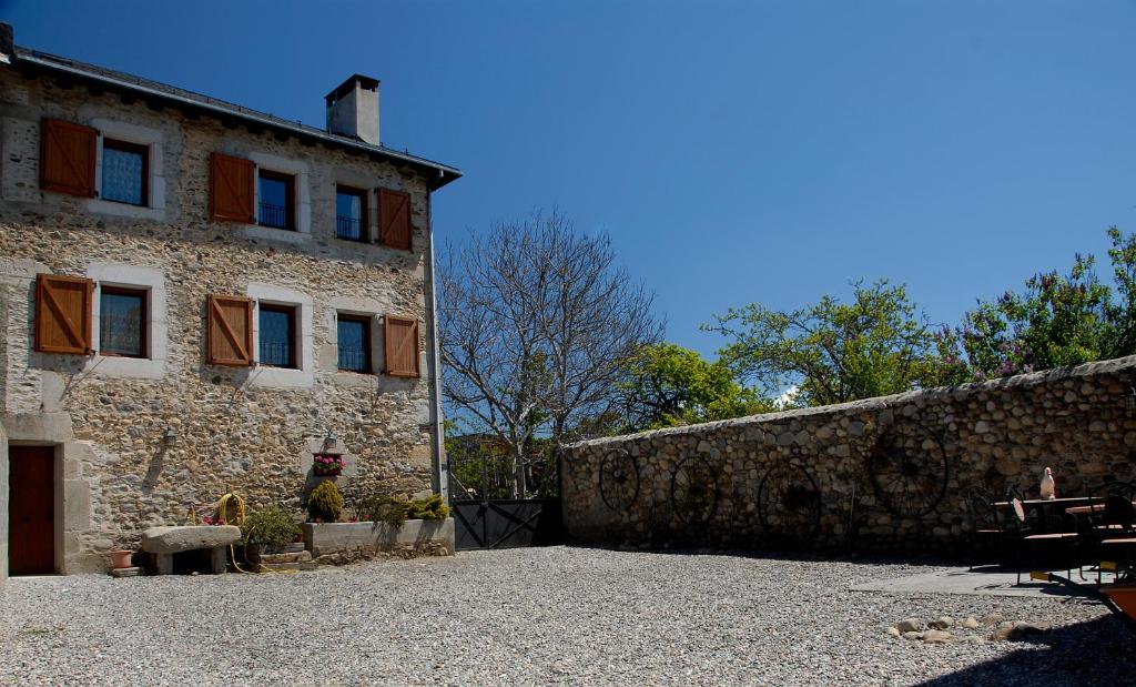 ein altes Steingebäude mit einer Steinmauer daneben in der Unterkunft Mas Mallol in Puigcerdà