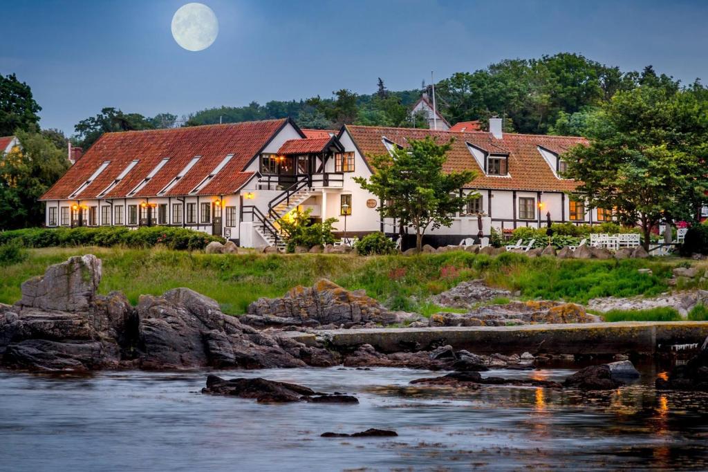 a house next to a river with a bridge at Allinge Badehotel in Allinge