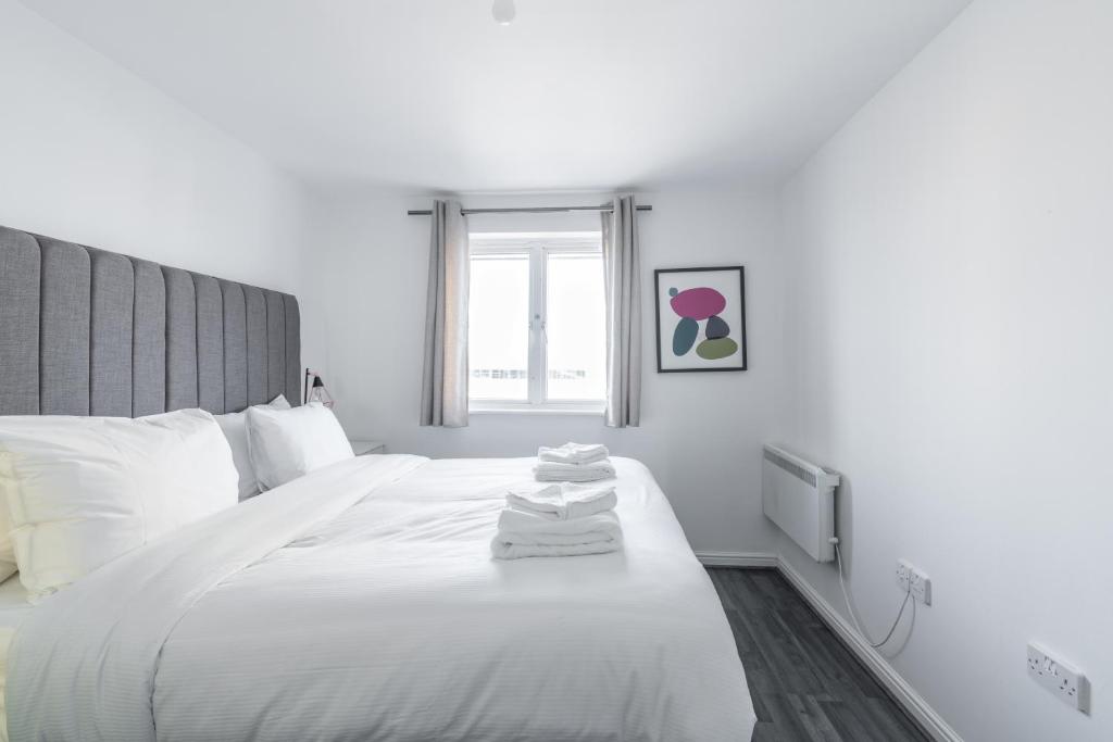 a bedroom with a white bed with towels on it at Suites by Rehoboth - Abbey Wood Station - London Zone 4 in London