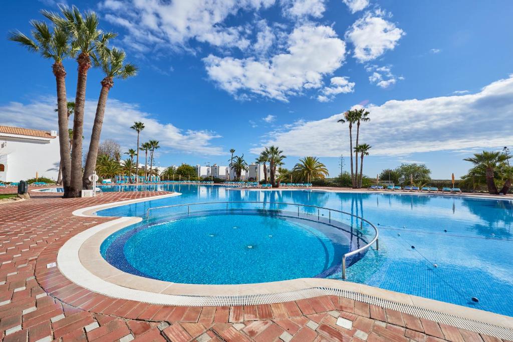a large swimming pool with palm trees in a resort at Beautiful Seaside Apartments in Tavira