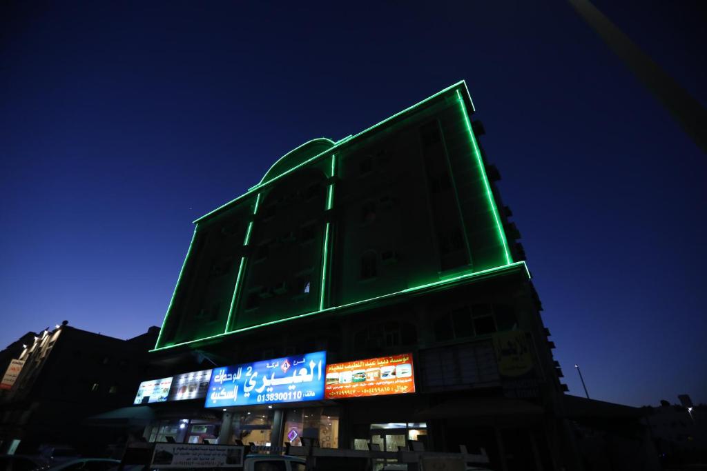 un edificio verde con señales en él por la noche en Al Eairy Apartments - Al-Damam 2, en Dammam
