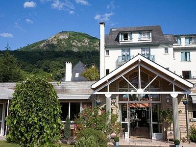 Une grande maison blanche avec une montagne en arrière-plan dans l'établissement Logis Hôtel Les Cimes, à Argelès-Gazost