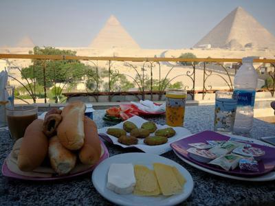 una mesa con platos de comida con pirámides en el fondo en Pyramids View Inn en El Cairo