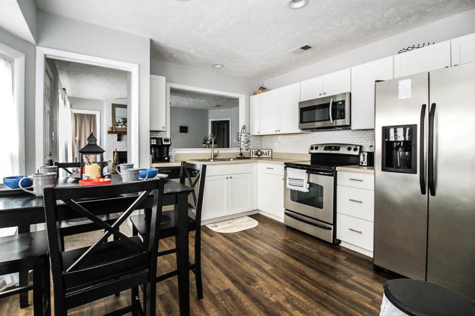 uma cozinha com armários brancos, uma mesa e electrodomésticos em Cozy cottage feel, 5 mins from Ft. Bragg em Fayetteville