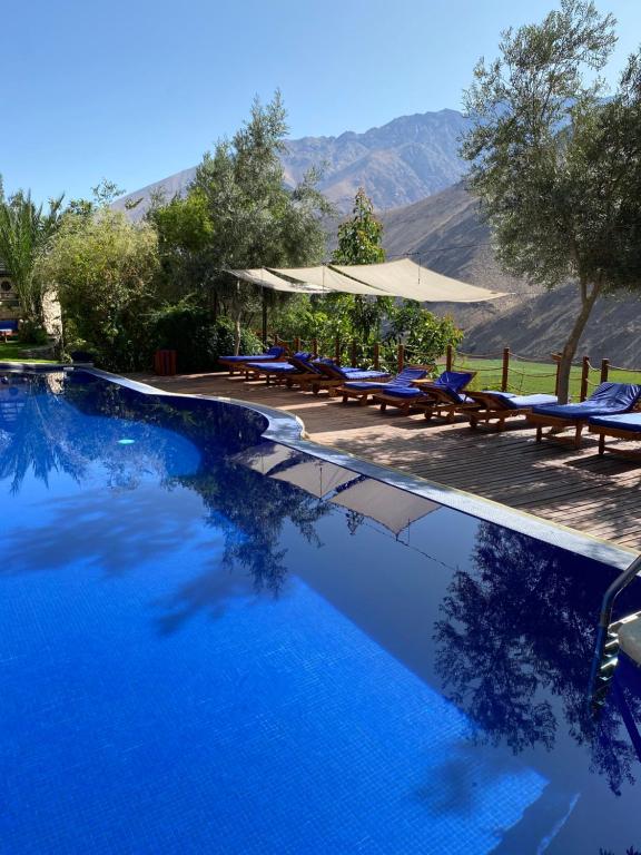 a swimming pool with tables and chairs and mountains at Cabañas Caballieri in Pisco Elqui