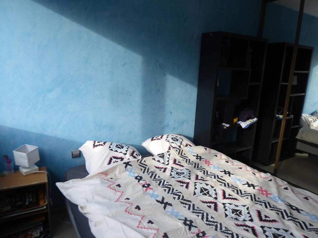 a bed in a room with a blue wall at Chambre dans un appartement Annecy Gare-Centre in Annecy