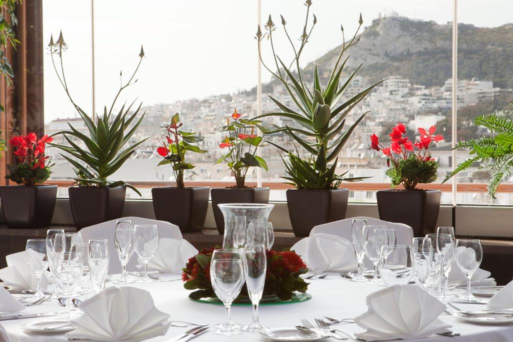 a table in a restaurant with glasses and flowers at Crowne Plaza Athens City Centre, an IHG Hotel in Athens