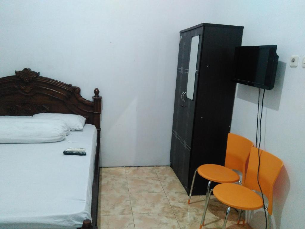 a bedroom with a bed and two chairs and a tv at Wisma Kahyangan in Baubau