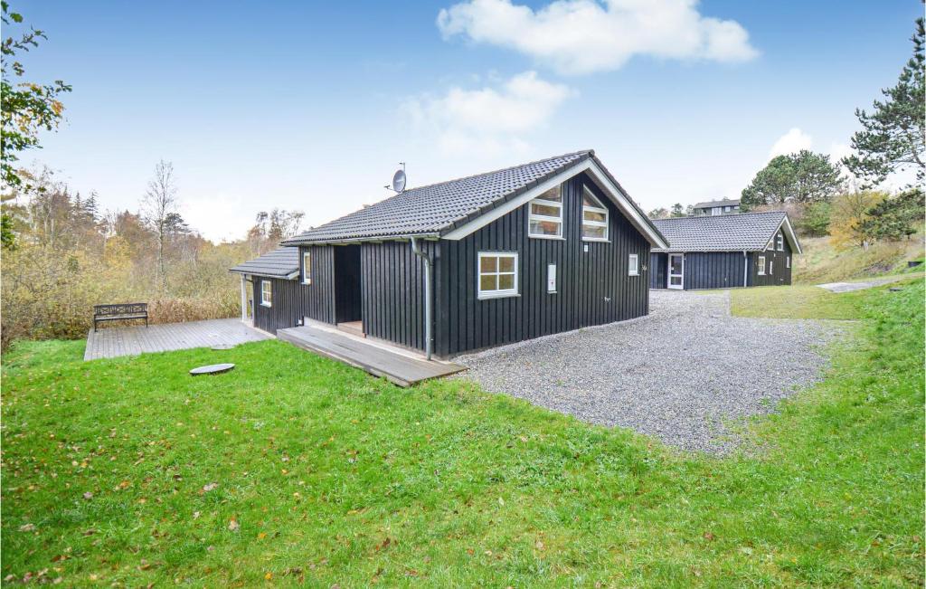 een zwart huis met een grindoprit in een tuin bij Stunning Home In Knebel With Kitchen in Ørby