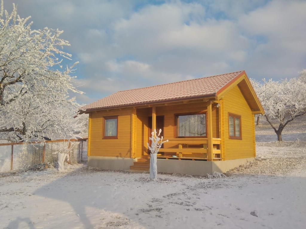 une petite maison jaune avec de la neige au sol dans l'établissement Country Garden - Országkert, à Păuleni-Ciuc
