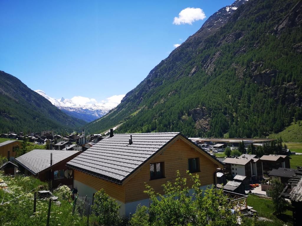 una casa in un villaggio con montagne sullo sfondo di Petit Paradisli a Täsch