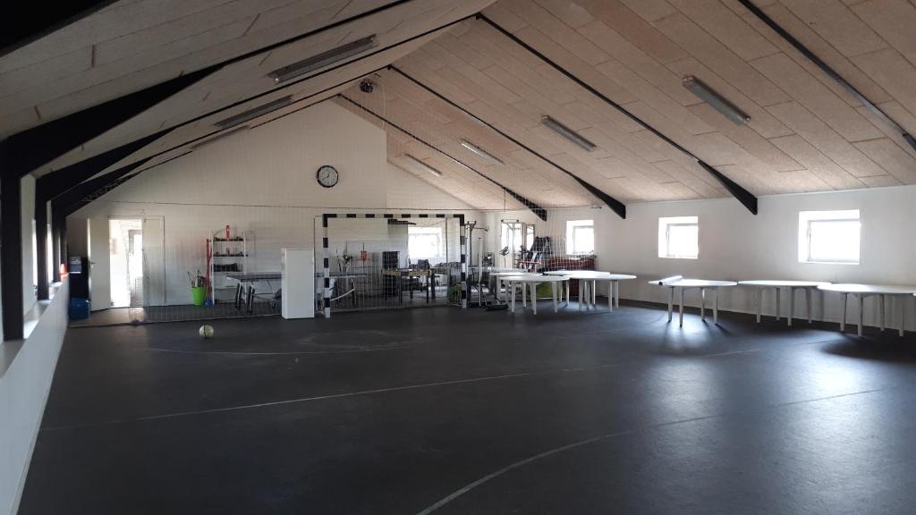 ein leeres Zimmer mit Tischen und Stühlen und einer Uhr in der Unterkunft Landsted med aktivitethal in Karby