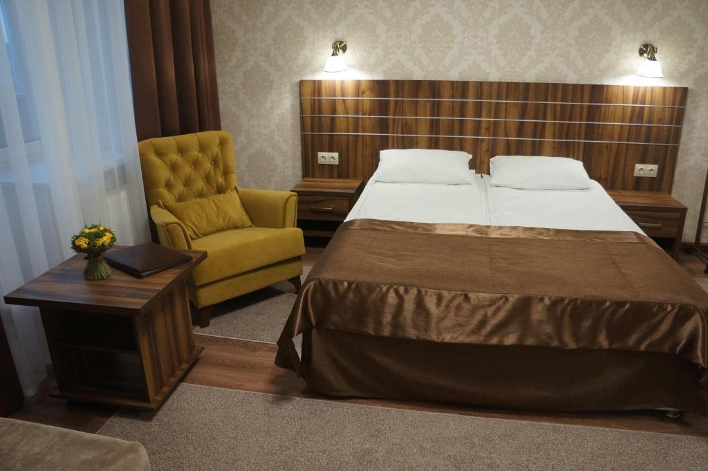 a bedroom with a bed and a yellow chair at Petrovsky Hotel in Kamensk-Shakhtinskiy