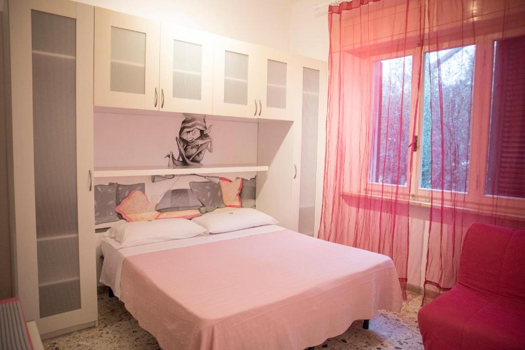 a bedroom with a white bed and a window at La Zattera Camere in San Vincenzo