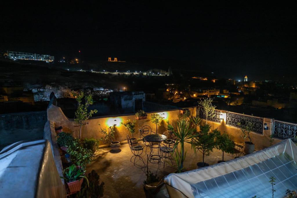 a rooftop patio with a table and chairs at night at Dar Naima in Fez