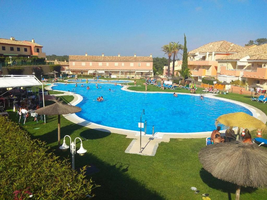 uma grande piscina com pessoas num resort em Islantilla Palmeras Golf 2 em Islantilla