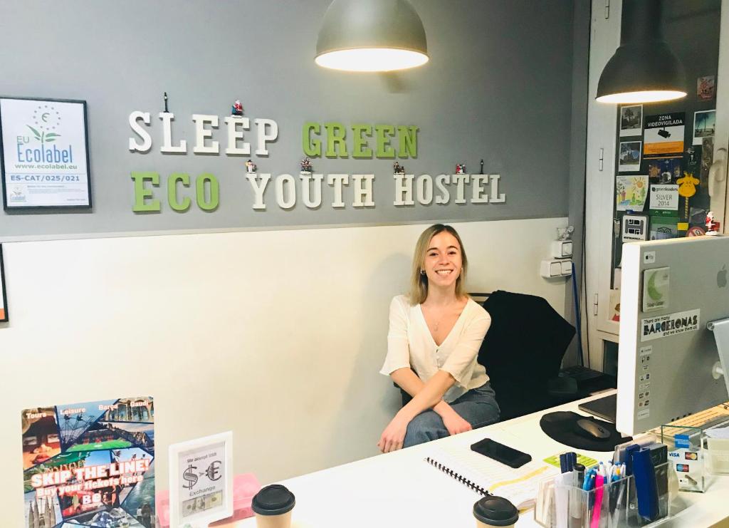 Eine Frau, die auf einem Schreibtisch in einem Büro sitzt. in der Unterkunft Sleep Green - Certified Eco Youth Hostel in Barcelona