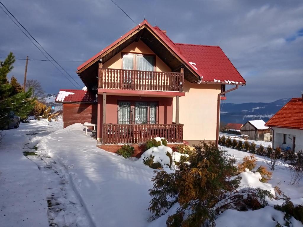 ein Haus mit rotem Dach im Schnee in der Unterkunft Domek u Jana in Istebna