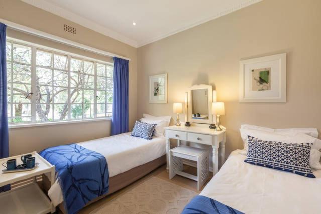 1 dormitorio con 2 camas, TV y ventana en Tiree B&B, en Johannesburgo
