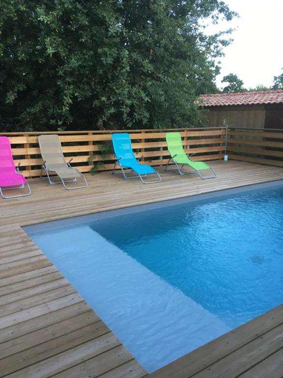 three chairs and a swimming pool on a wooden deck at comme chez vous in Taussat-les-Bains