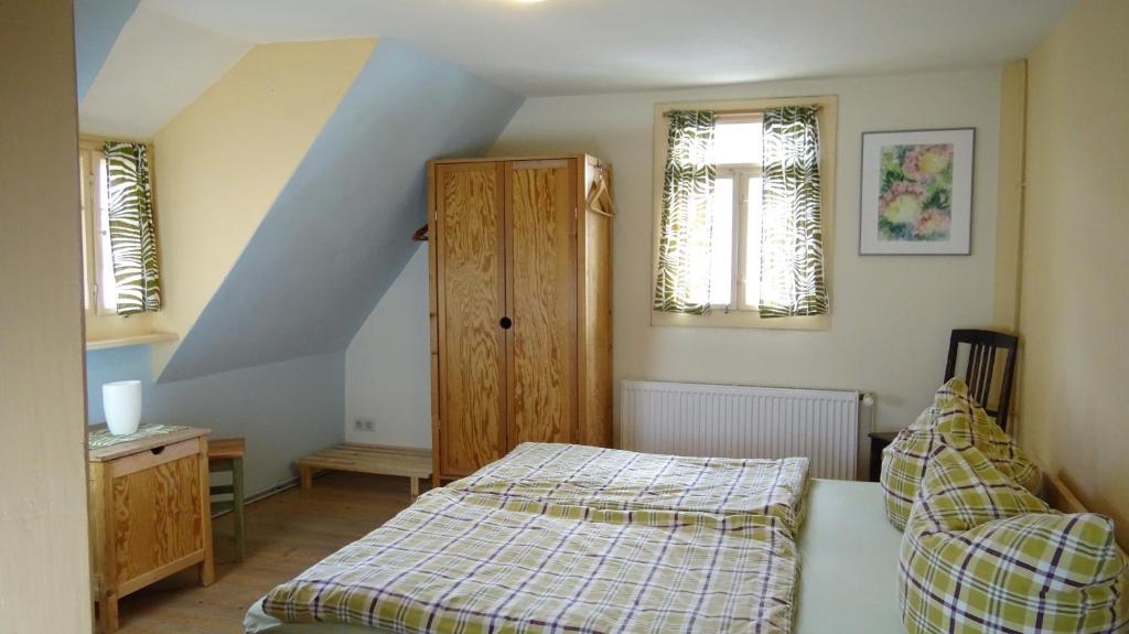 ein Schlafzimmer mit einem Bett, einem Schrank und zwei Fenstern in der Unterkunft Ferien im Denkmal an der Elbe in Stadt Wehlen