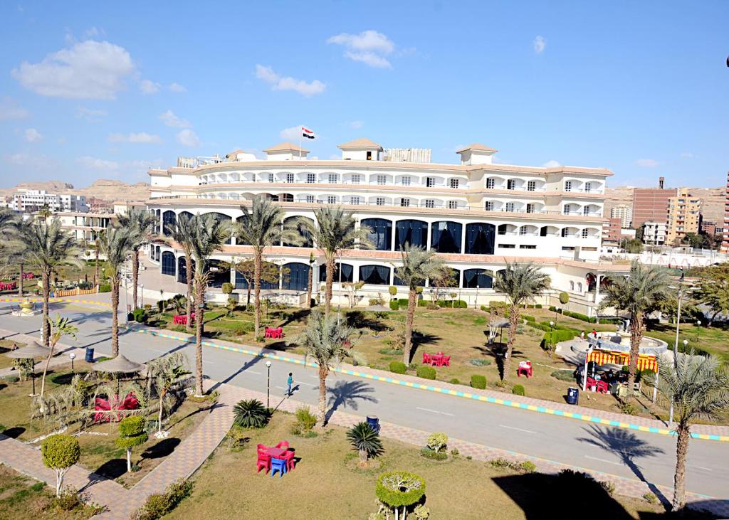 a large white building with palm trees and a street at Minya Compound of the Armed Forces in Minya