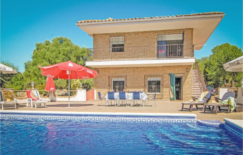 a house with a swimming pool and a red umbrella at Awesome Home In Almodvar Del Ro With 5 Bedrooms, Wifi And Outdoor Swimming Pool in Almodóvar del Río