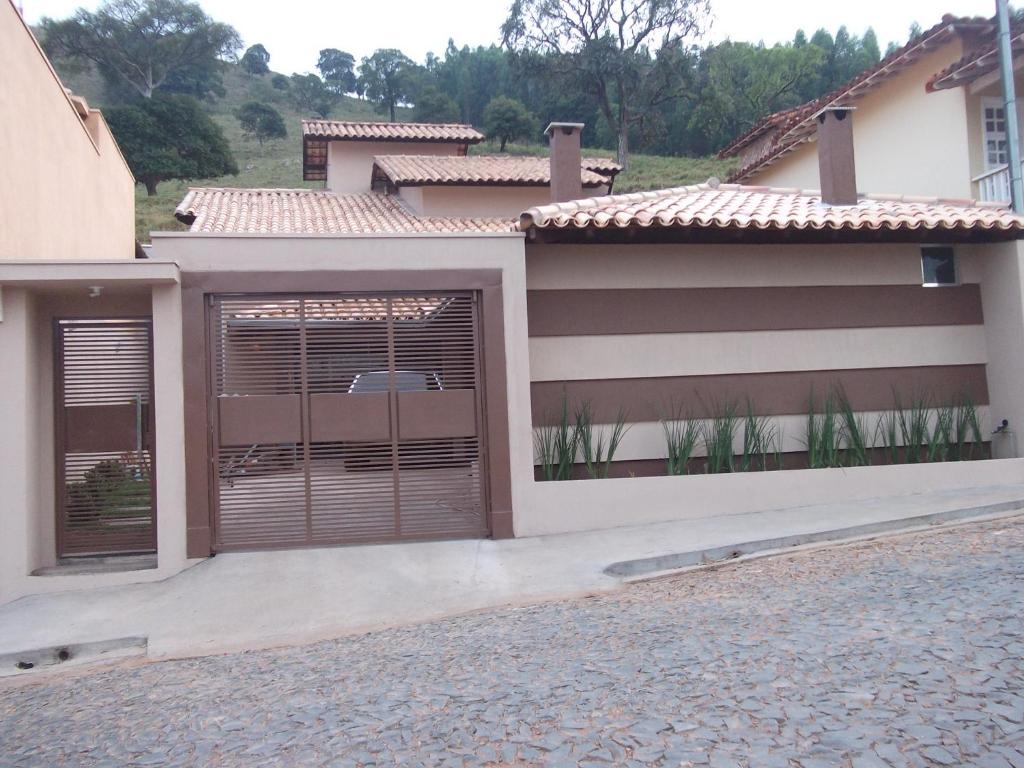 a house with two garage doors and a driveway at Casa Temporada Patricia Lima in Capitólio