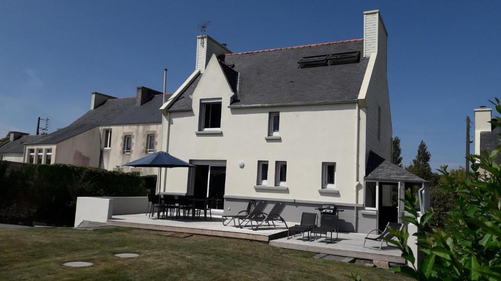 a white house with some chairs and tables in front of it at Maison de vacances à proximité de la plage in Saint-Pabu