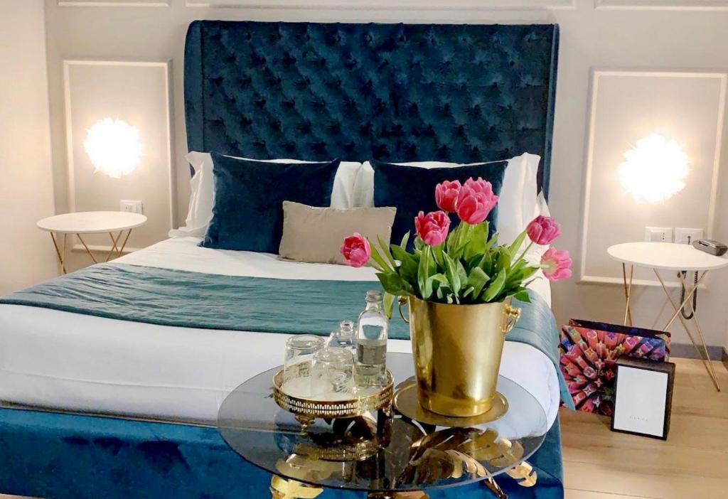a bedroom with a blue bed with a glass table with flowers at INTOMILAN Galleria Duomo I Boutique & Design Aparthotel in Milan