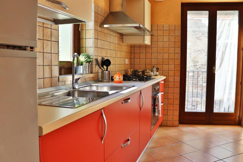 eine Küche mit roten Schränken und einem Waschbecken in der Unterkunft Sotto al Portico - YourPlace Abruzzo in Rocca San Giovanni
