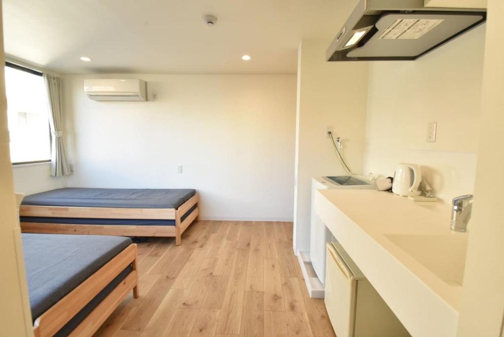 Habitación pequeña con 2 camas y lavamanos en Enzo Tokyo en Tokio