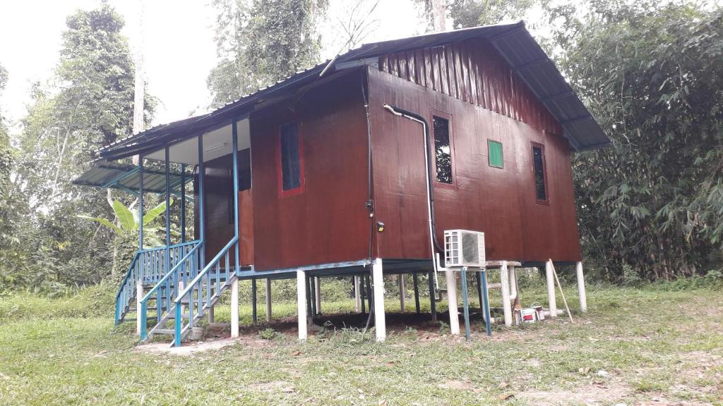 a large red cabin with stairs in a forest at Chalet Kampong Guar, Manong in Kuala Kangsar