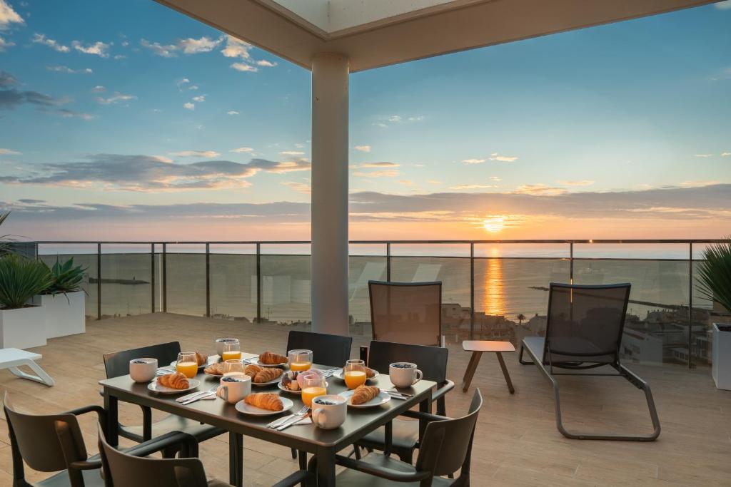 Ahoy Apartments في إل كامبيلو: طاولة مع الطعام على شرفة مع غروب الشمس