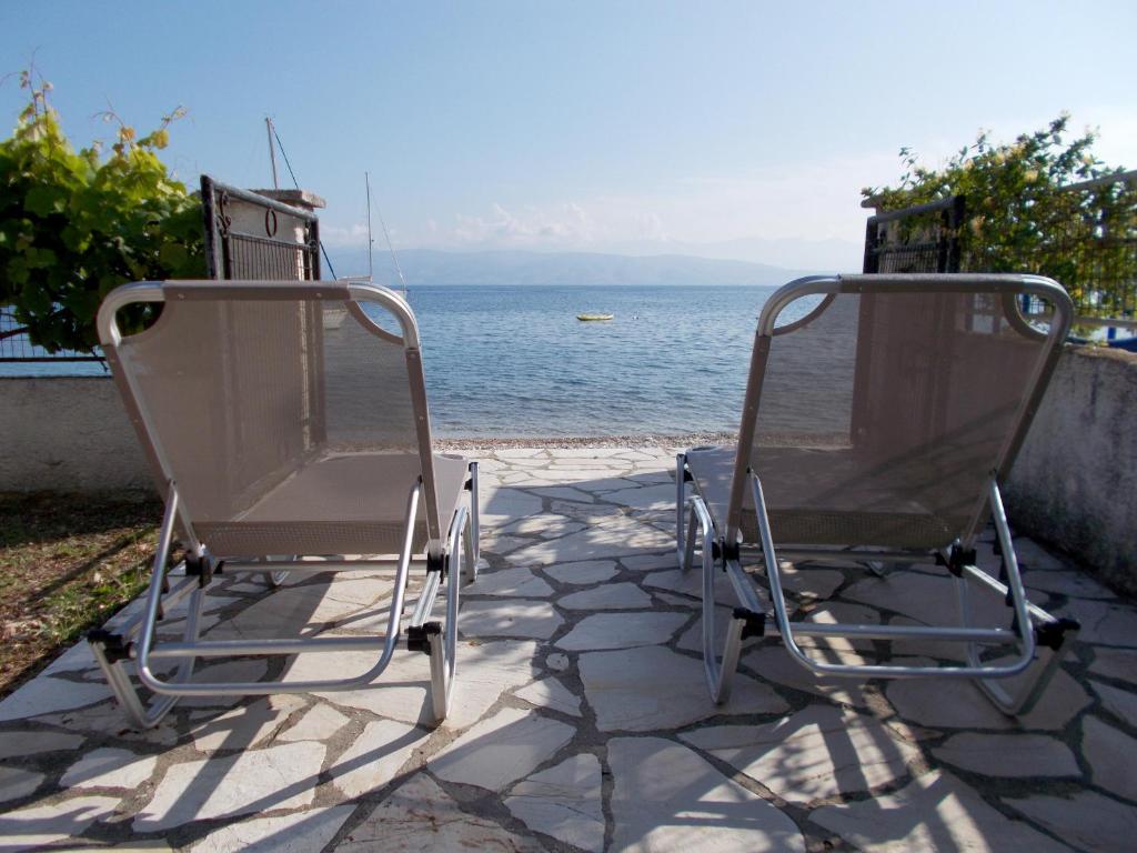 2 sillas sentadas en un patio junto al agua en Eva Apartments, en Kassiopi