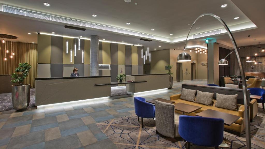 a hotel lobby with a reception desk and blue chairs at Crowne Plaza Aberdeen Airport by IHG in Dyce