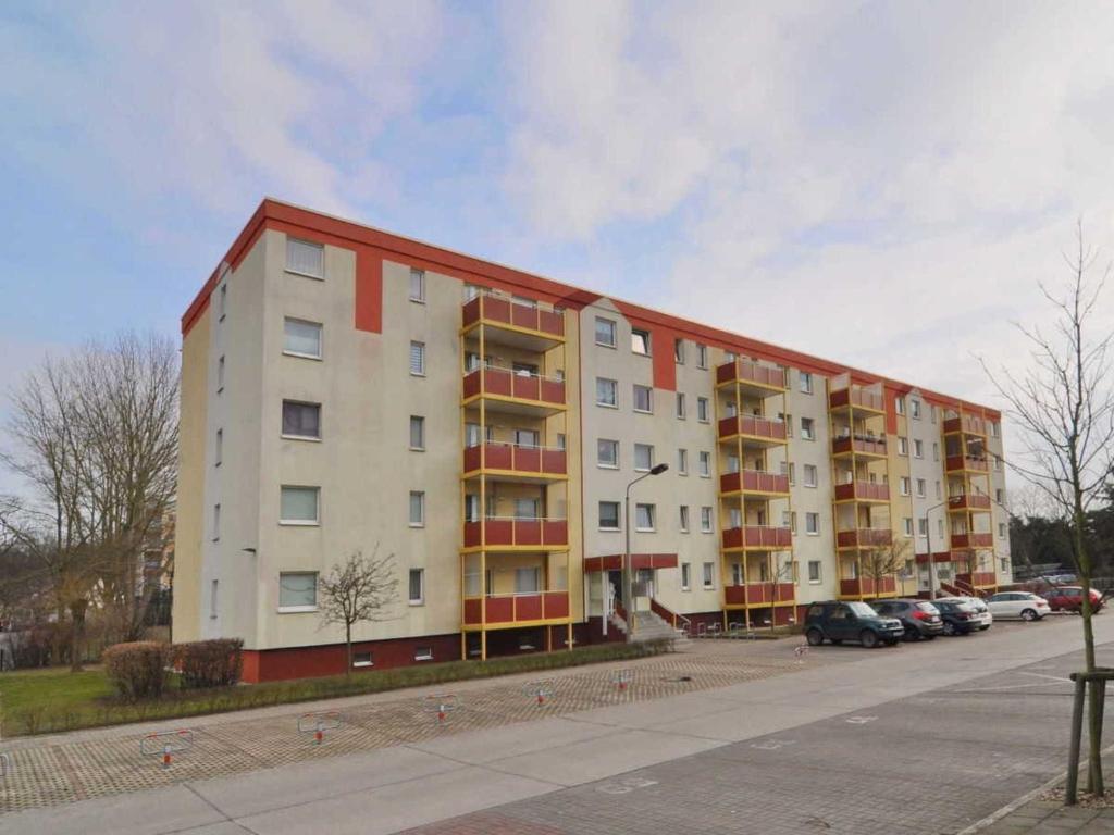 ein großes Apartmenthaus mit Autos auf einem Parkplatz in der Unterkunft Ferienwohnung Dünenweg Piepen in Heringsdorf