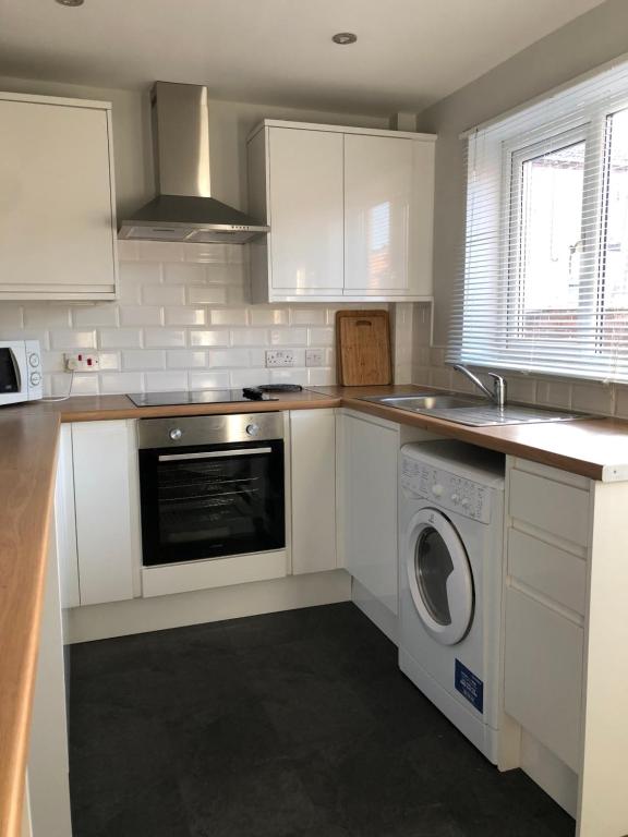 a kitchen with white cabinets and a washer and dryer at spacious 2 bedroom house in Shotton