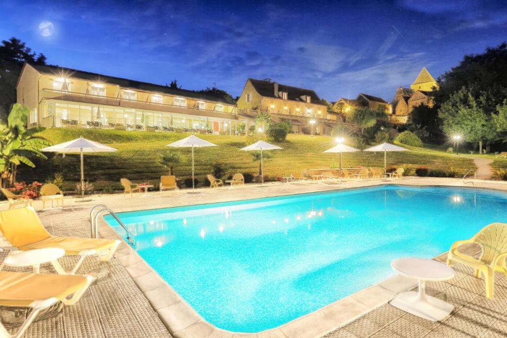 una piscina en un hotel con sillas y sombrillas en Hotel Restaurant Laborderie, en Tamniès