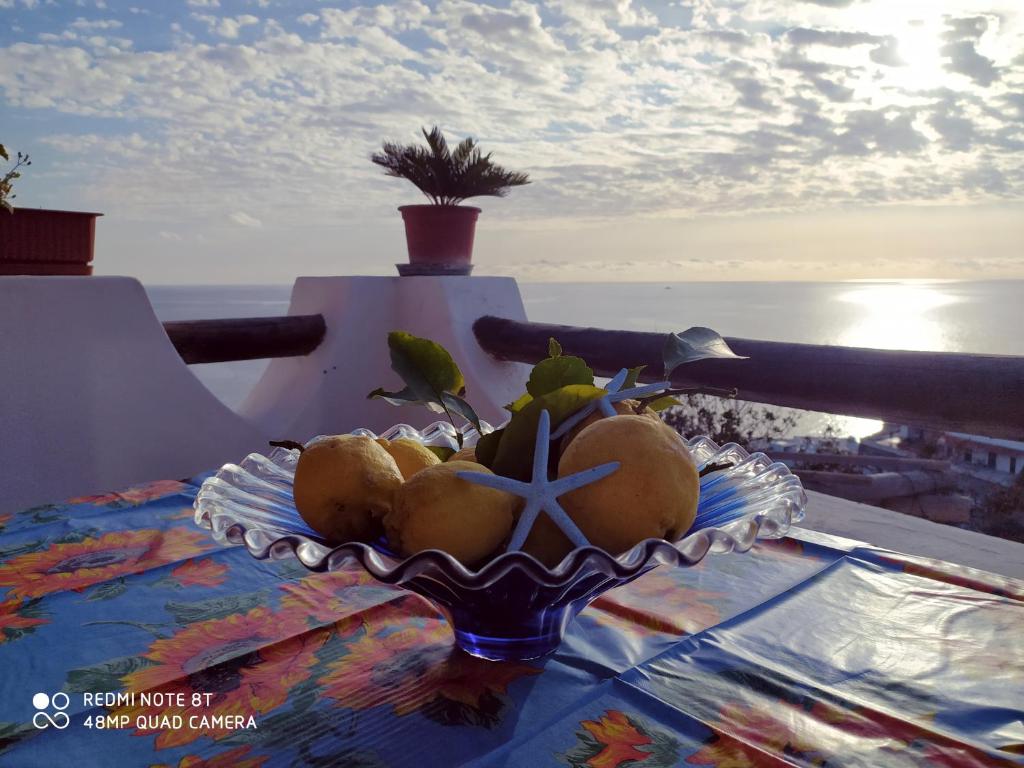 un cesto di frutta su un tavolo con l'oceano sullo sfondo di Casa Bianca A S'Angelo a Ischia