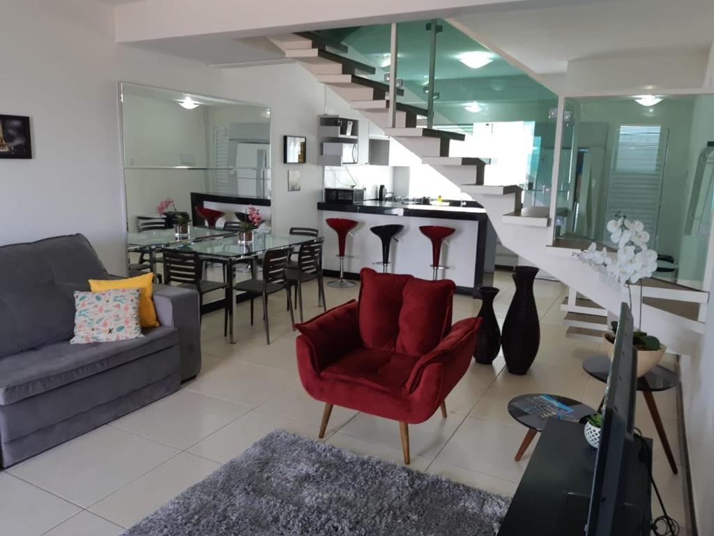 a living room with a couch and a red chair at Mirante de Escarpas 1402 in Capitólio