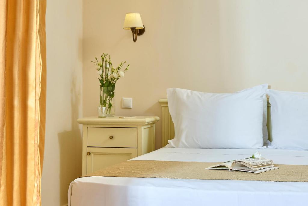 a bed with a book and a vase of flowers on it at Vasia Resort & Spa in Sisi