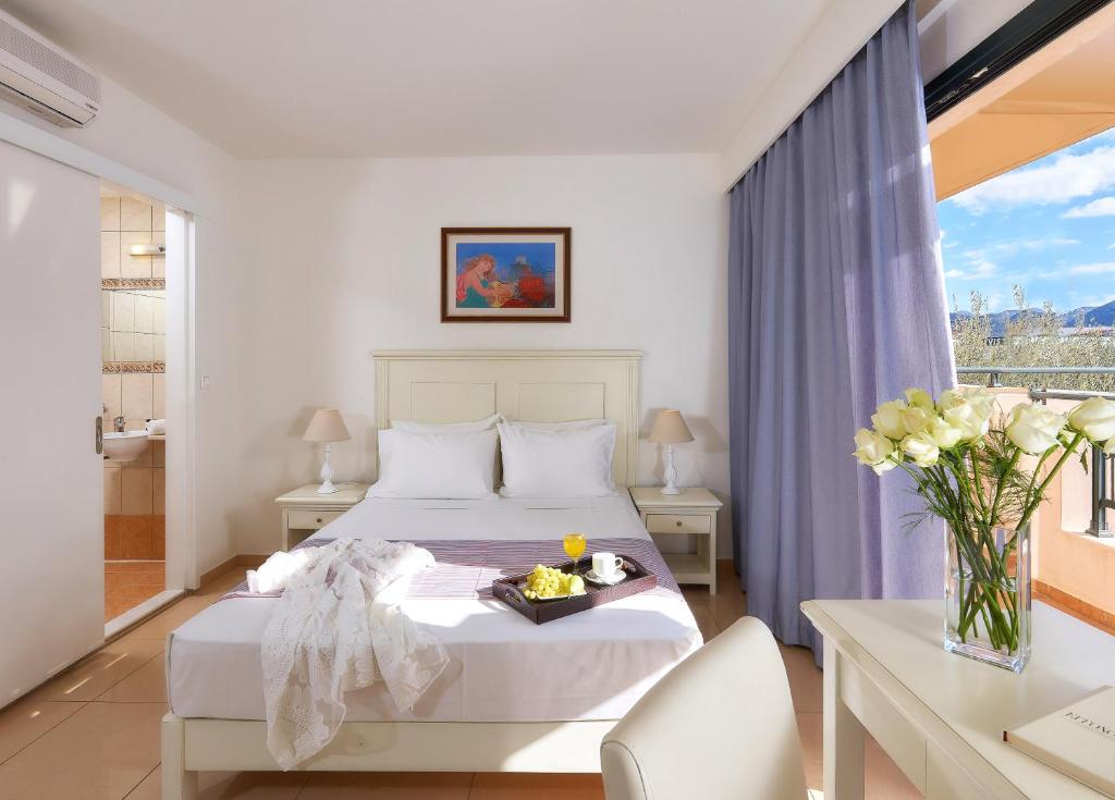 a bedroom with a bed with a tray of food on it at Vasia Resort & Spa in Sisi