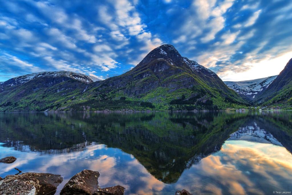 un reflejo de montaña en un lago con un cielo nublado en Trolltunga Camping, en Odda