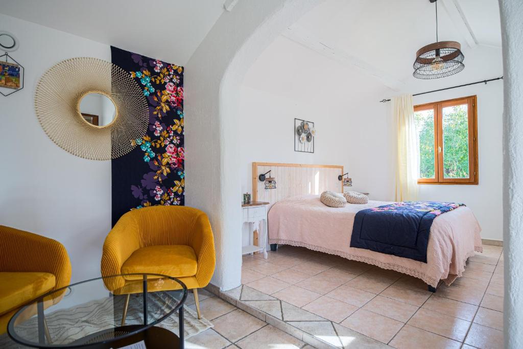 a bedroom with a bed and a chair and a table at A l'Orée du Pin in Puyricard