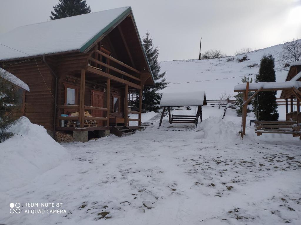 ein Blockhaus mit Schnee auf dem Boden in der Unterkunft ЕКО-котедж in Werchowyna