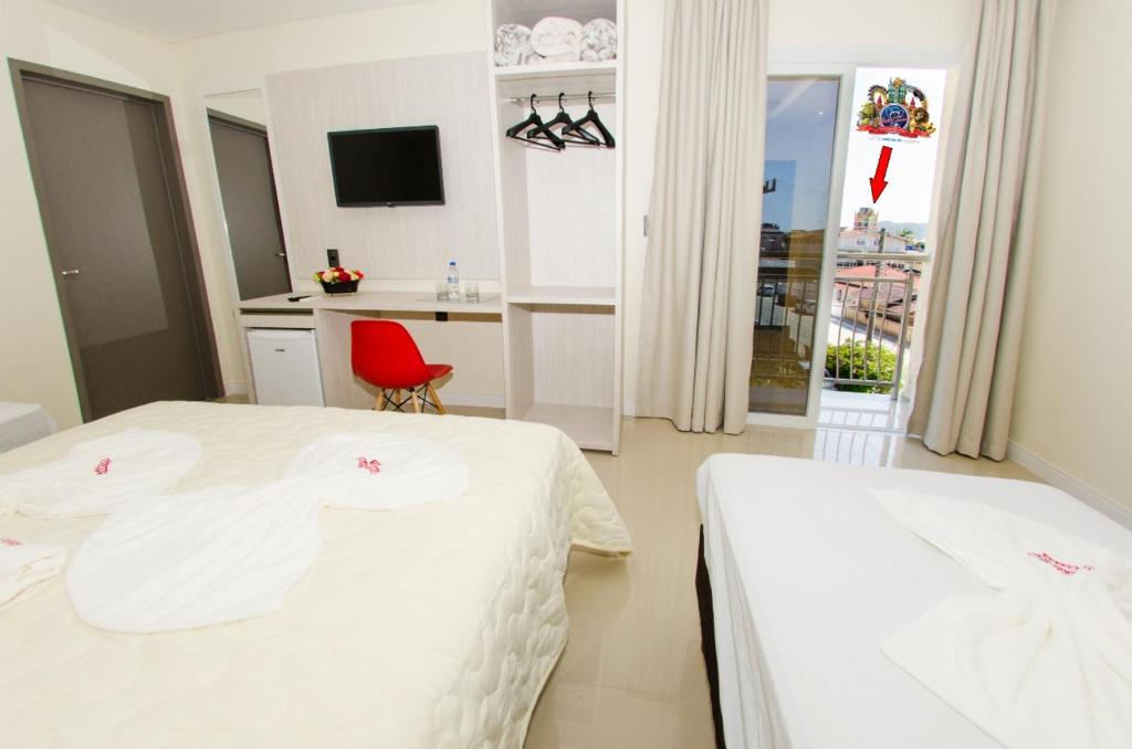 um quarto de hotel com duas camas e uma cadeira vermelha em Hotel Balneário do Parque em Penha