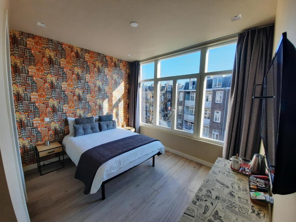 um quarto com uma parede de tijolos, uma cama e uma grande janela. em RoomWest em Amsterdã