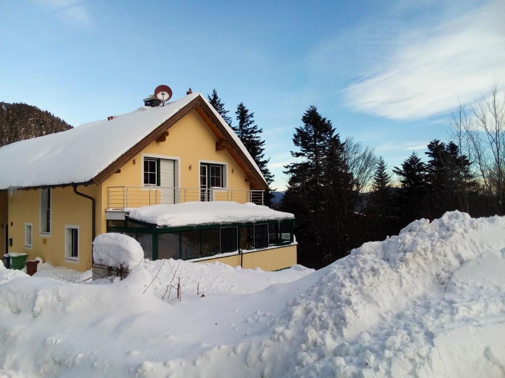 a house covered in snow next to a pile of snow at Ferienhaus Anna Semmering in Semmering