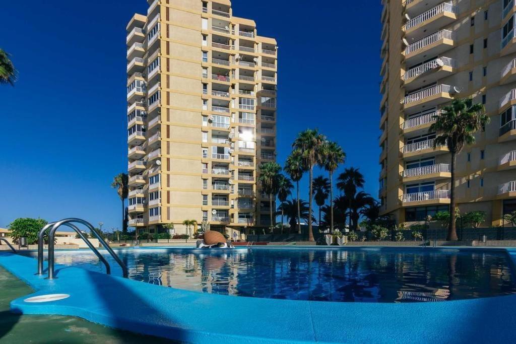 una piscina frente a un edificio alto en Torres de Yomely Playa las Americas, en Playa de las Américas